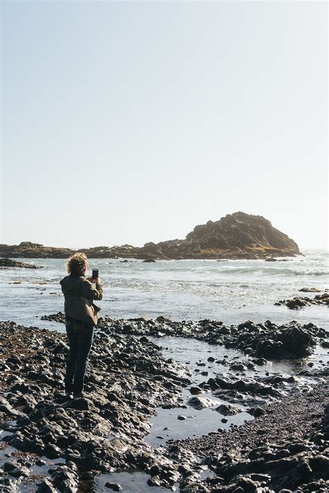 "Older Woman On The Beach Taking Photo On Phone" by Stocksy Contributor