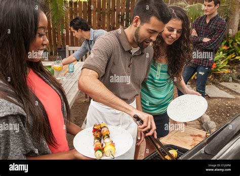 Friends sitting around table sharing barbecue food Stock Photo - Alamy